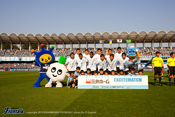 試合前の集合写真。新マスコットの「コムゾーくん」も参戦。